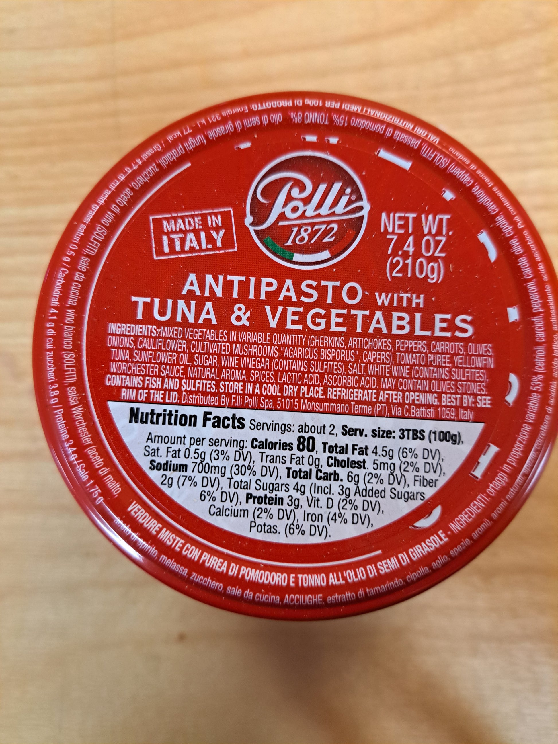 Red lid of a Pelati antipasto with tuna and vegetables container on a wooden surface
