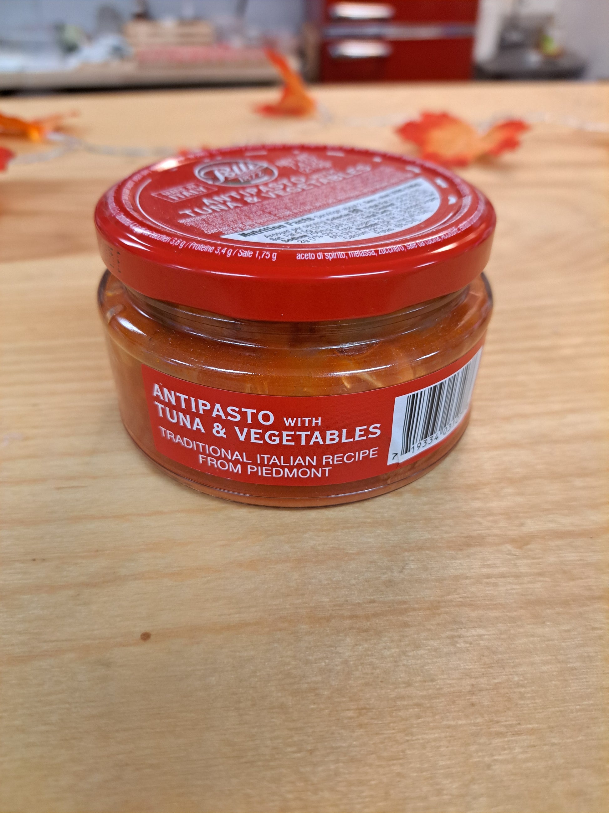 Jar of antipasto with tuna and vegetables on a wooden surface