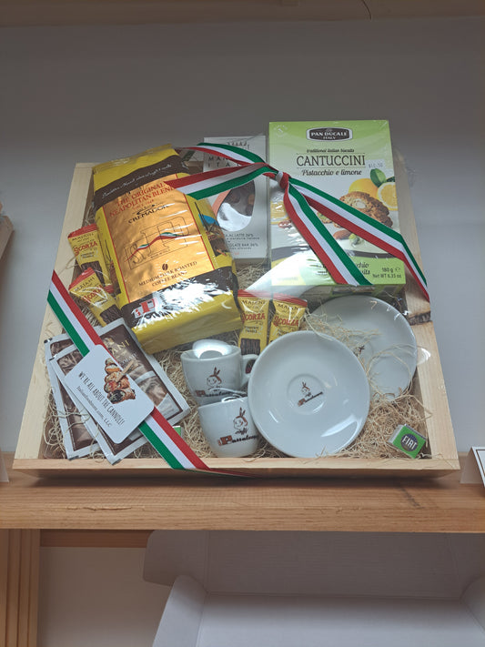 Gift box with Italian-themed products including pasta and a flag on a wooden surface.
