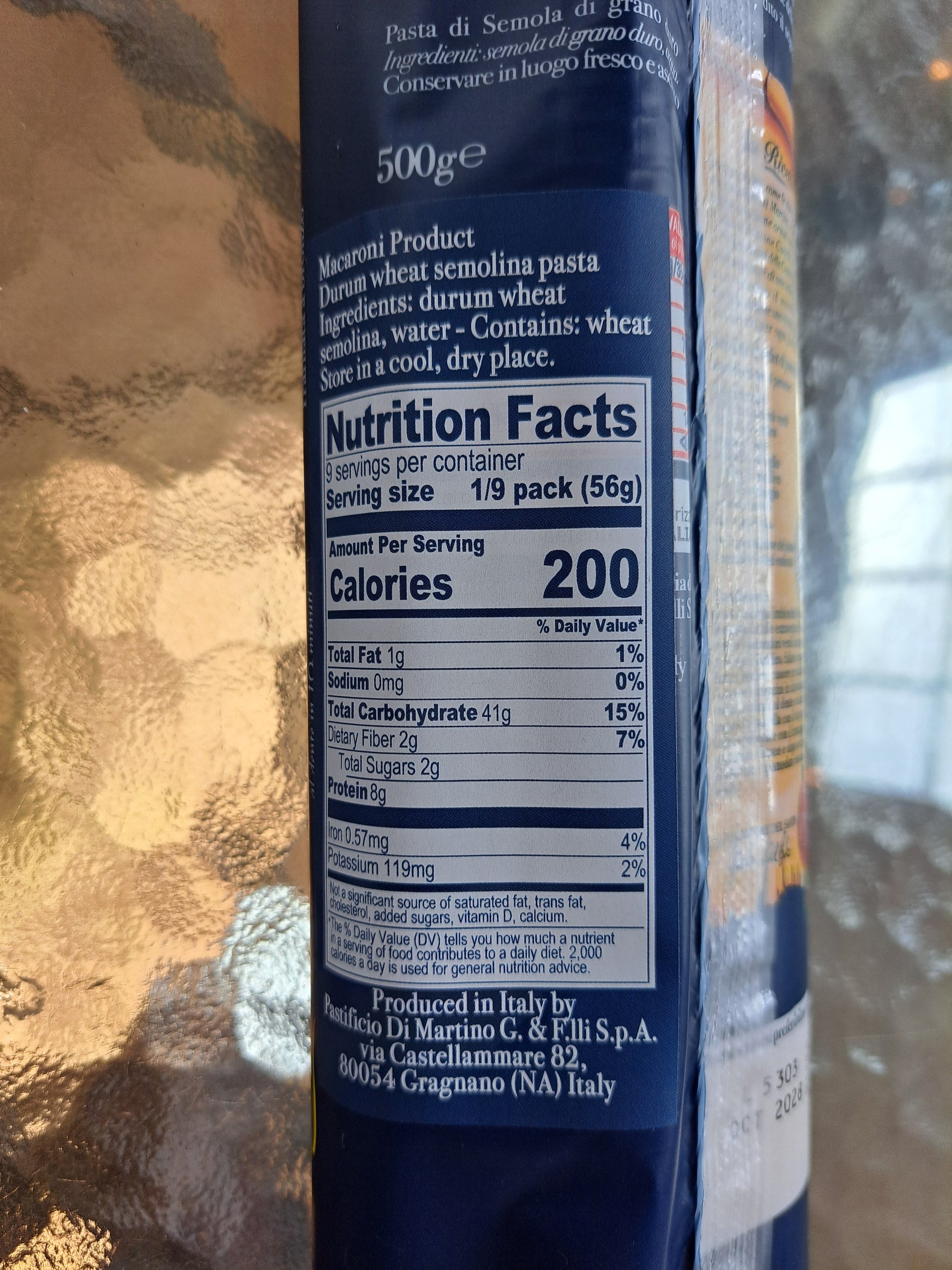 Nutrition facts label on a pasta packaging with a reflective gold surface.
