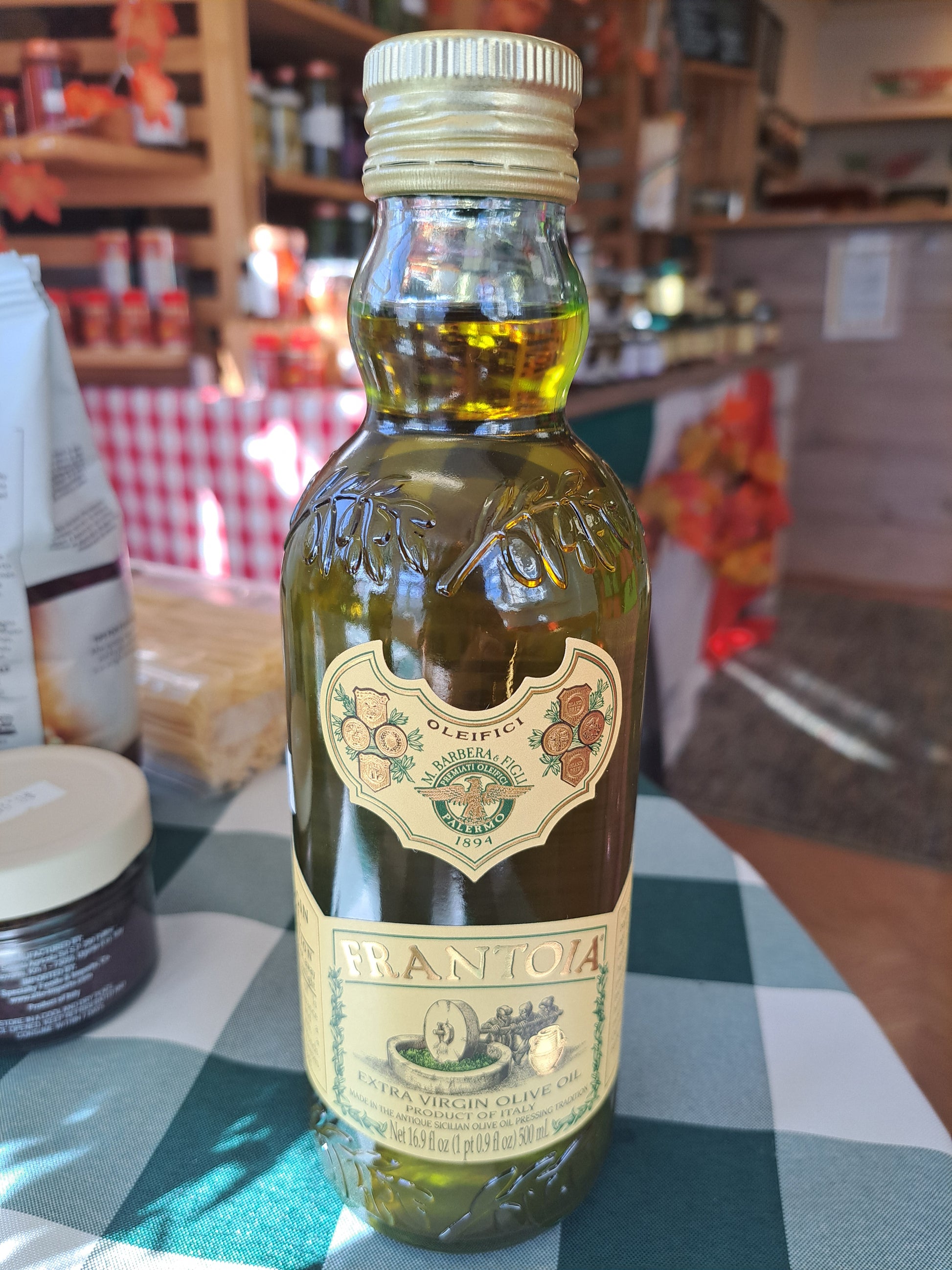 Bottle of olive oil with a label on a checkered tablecloth