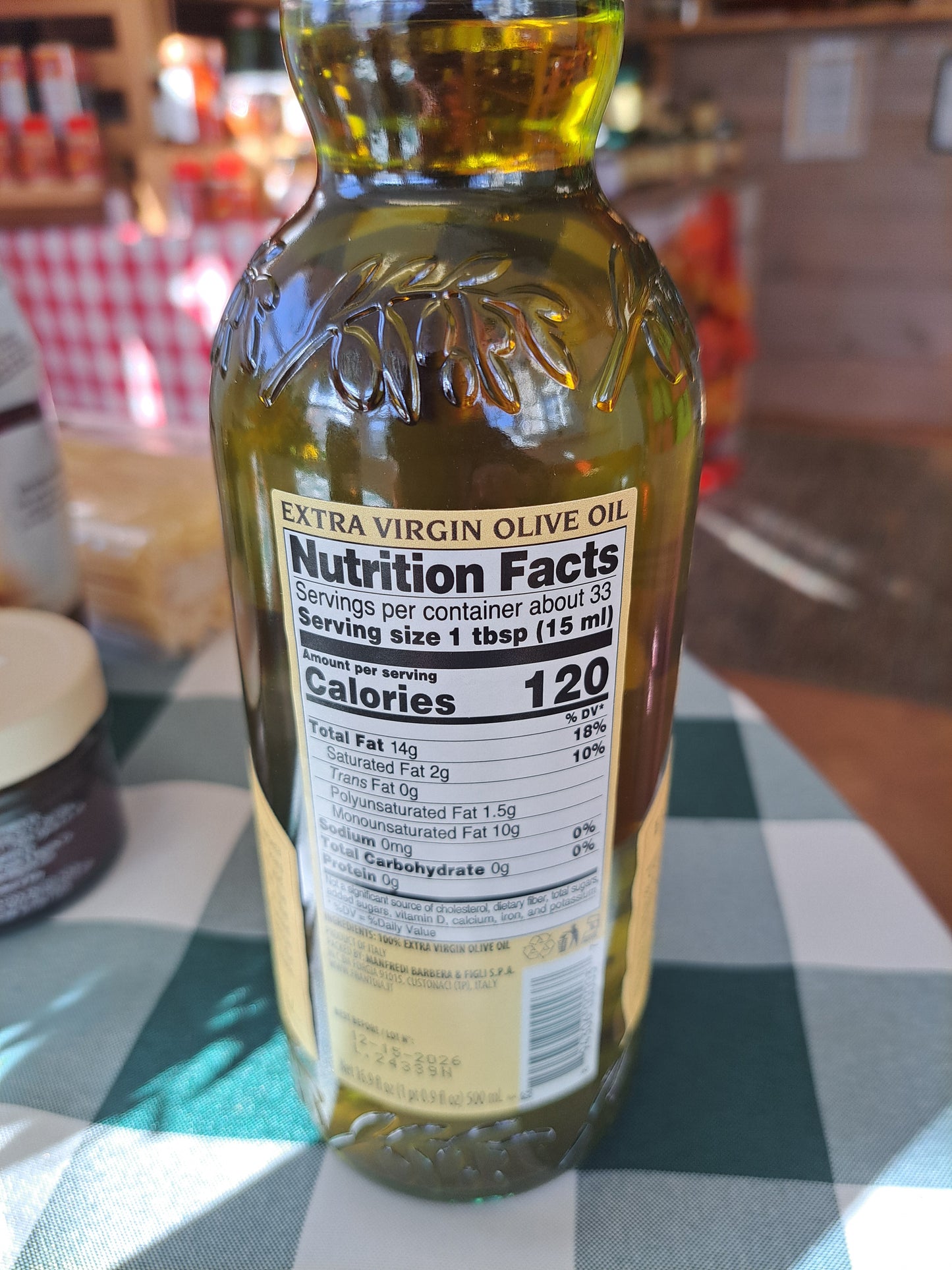 Bottle of extra virgin olive oil with label on a checkered tablecloth
