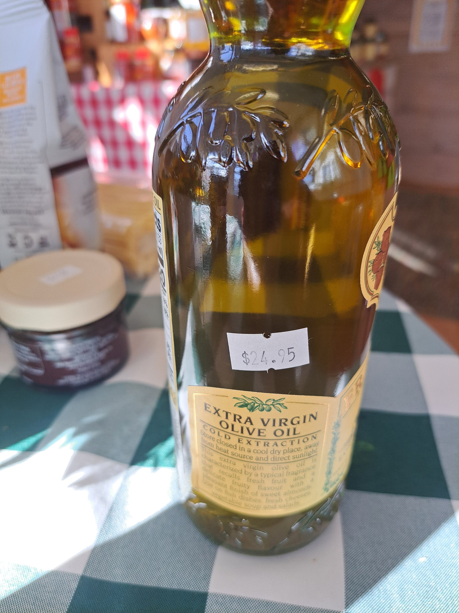 Bottle of extra virgin olive oil with a label on a checkered tablecloth