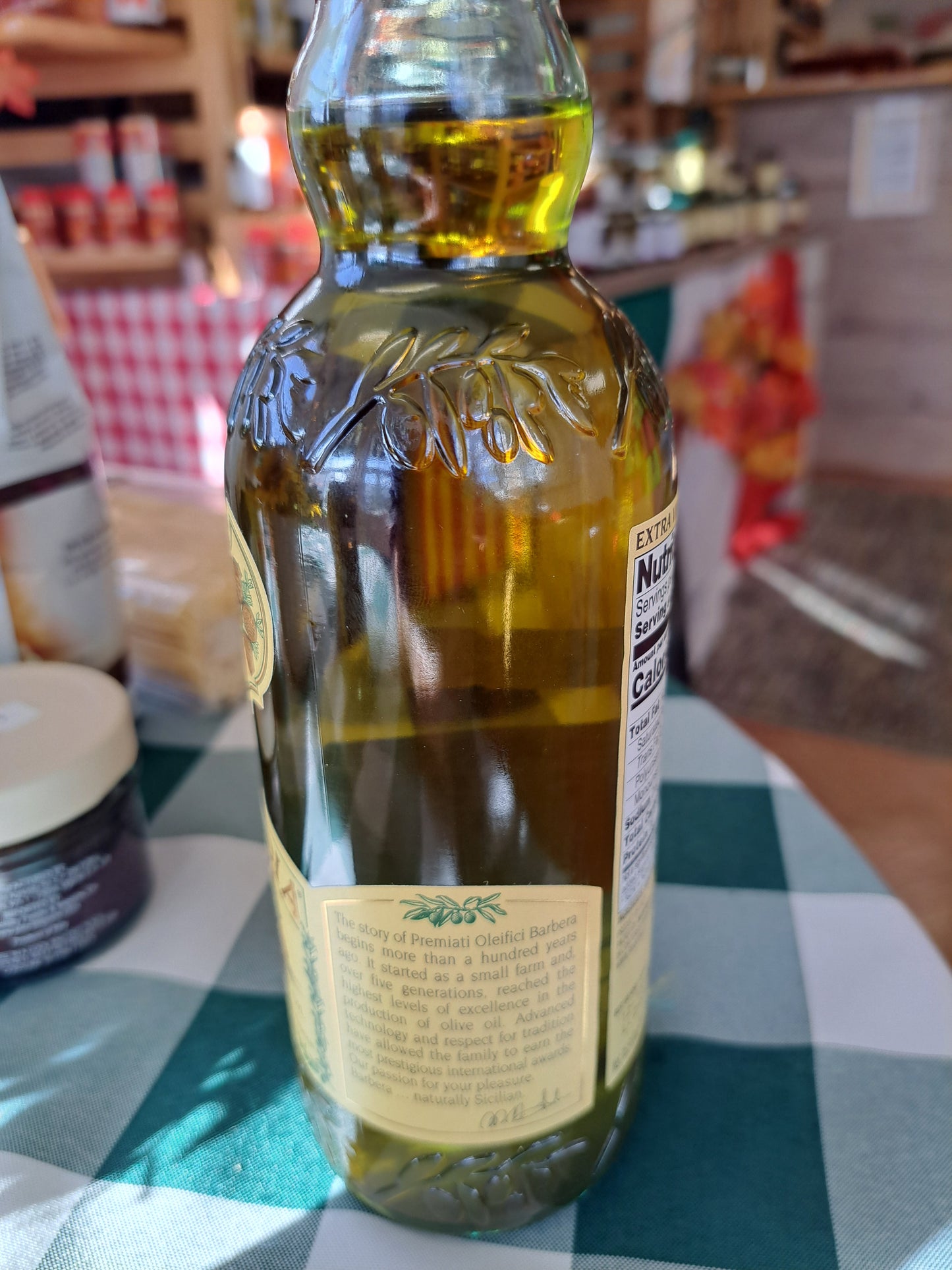 Bottle of olive oil on a checkered tablecloth with a blurred background