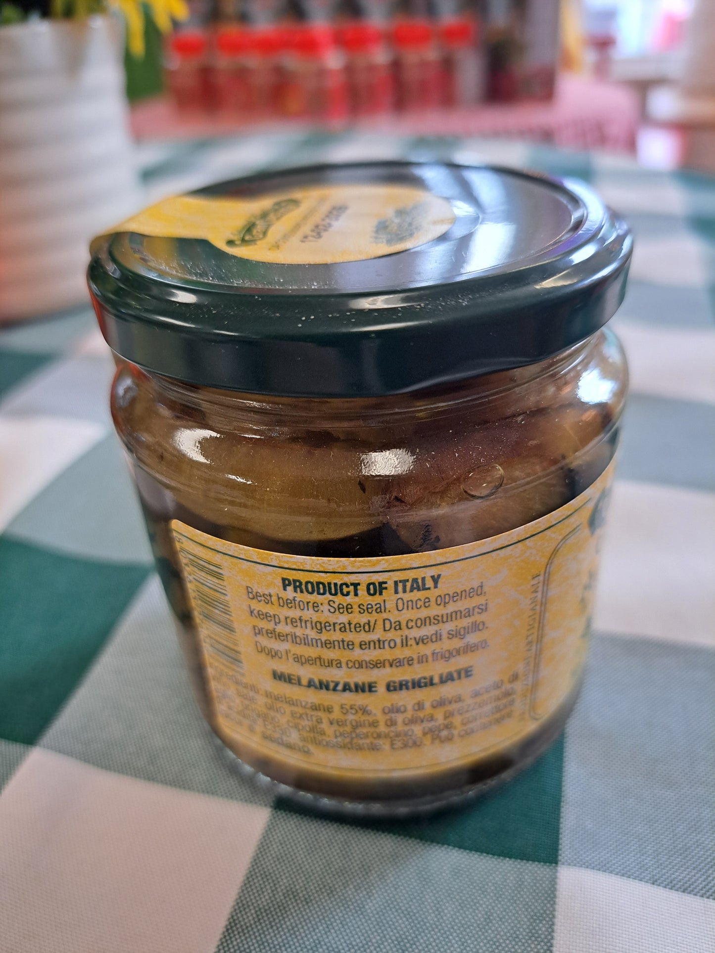 Jar of Grilled Aubergines with a label on a checkered tablecloth