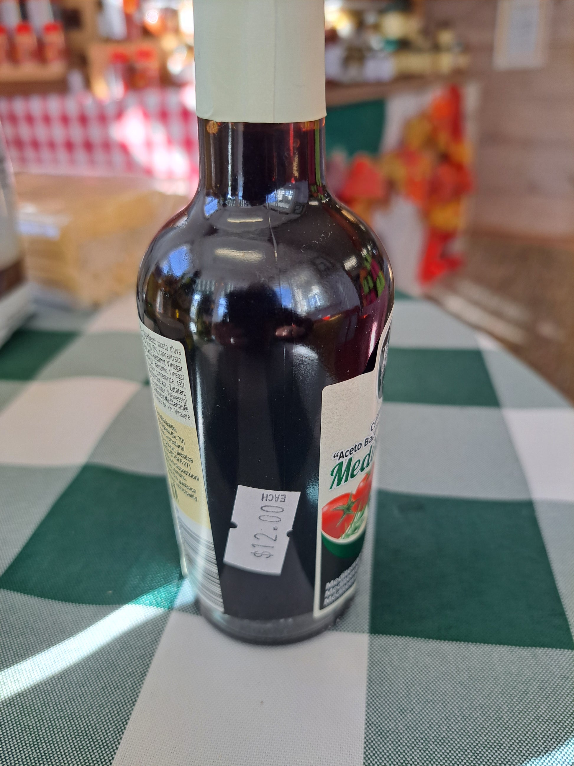 Bottle of olive oil with a label on a checkered tablecloth