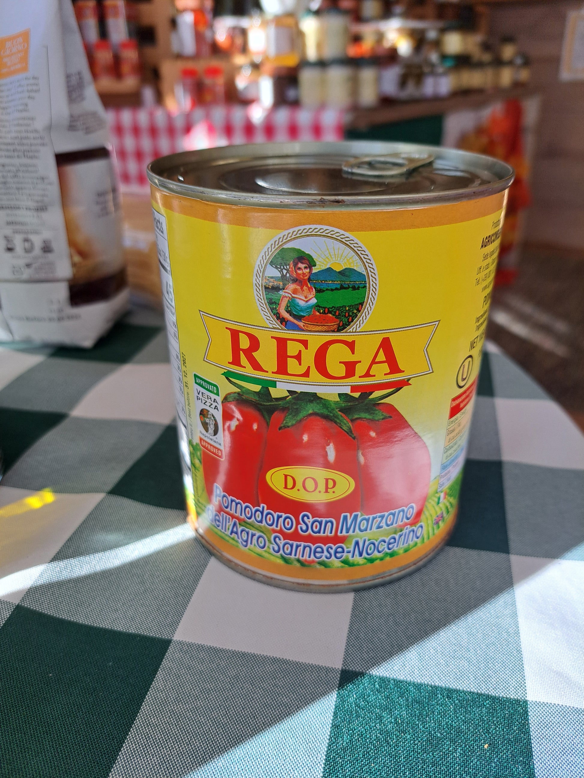 Can of Rega tomatoes on a checkered tablecloth